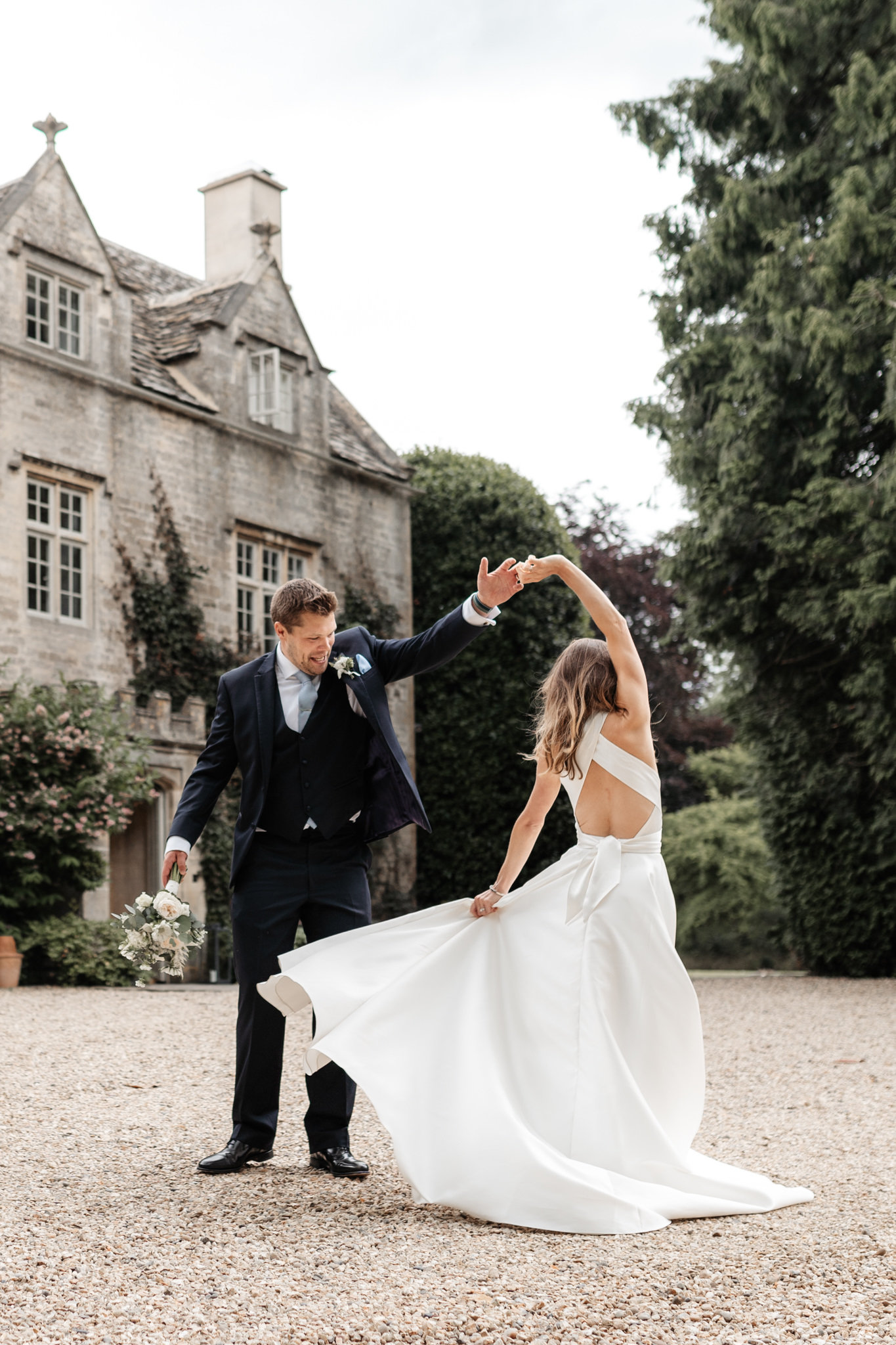 bride and groom dancing outside their wedding venue barnsley house in the cotswolds
