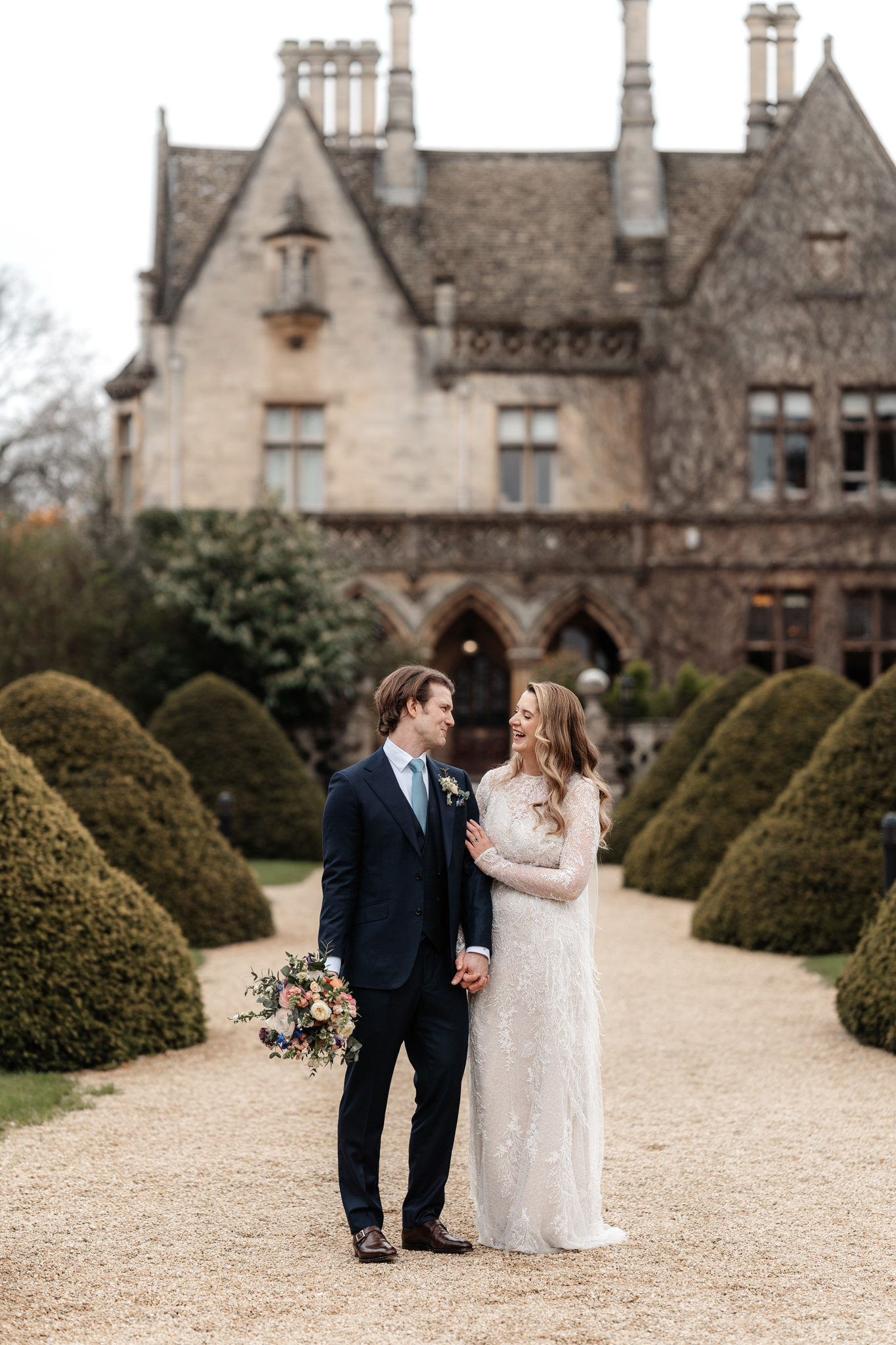 bride and groom portrait outside their wedding venue manor by the lake in cotswolds