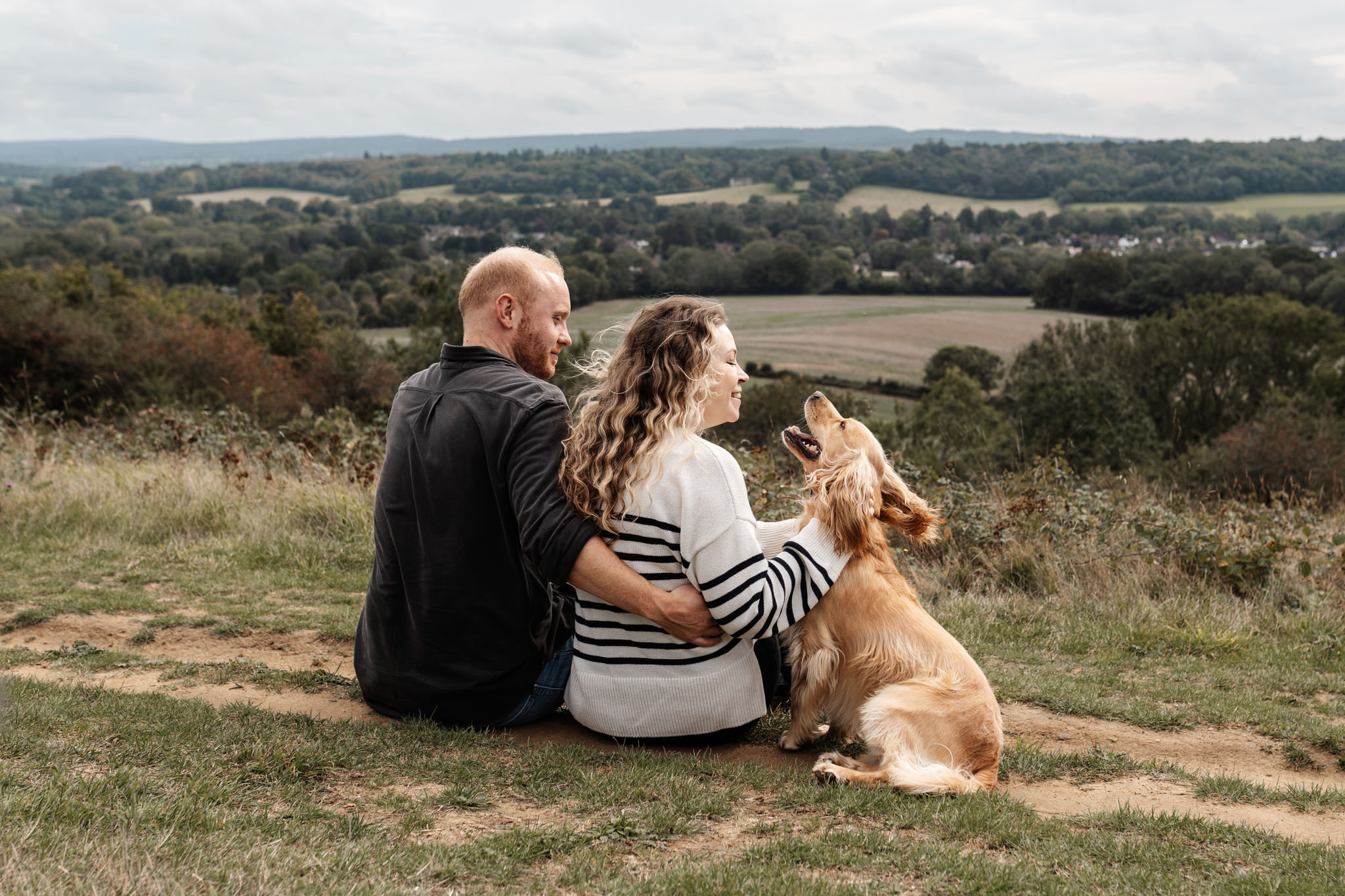 couple joyfully playing with their dog during their engagement session in surrey