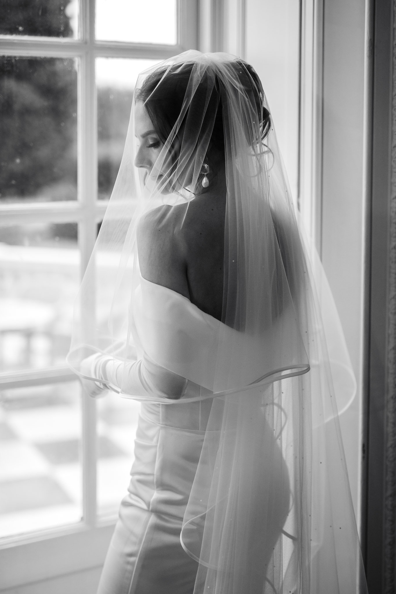 editorial style portrait of a bride standing in front of a window before her wedding