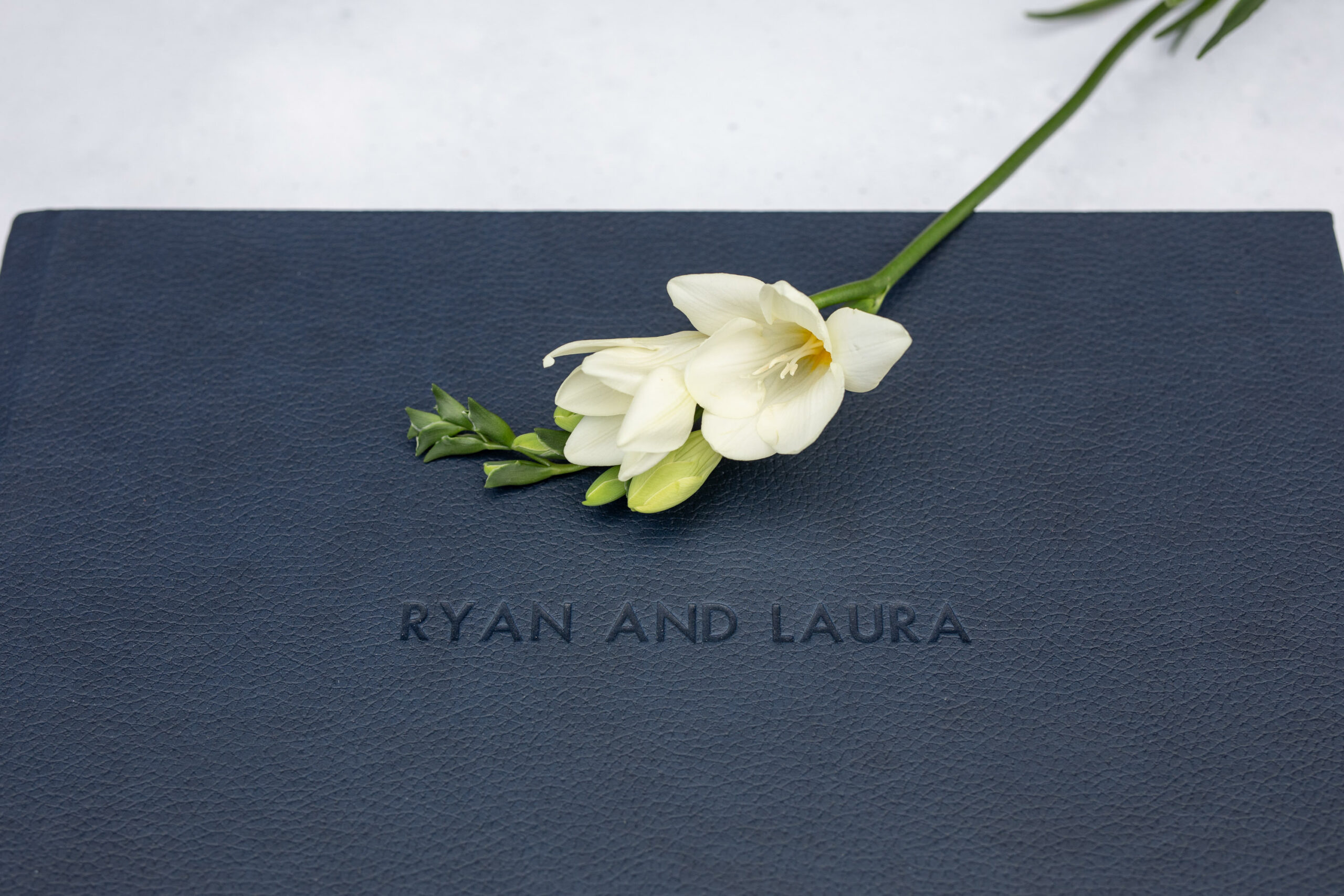 embossed front cover of a luxury wedding album with a beautiful flower gracefully sitting on top