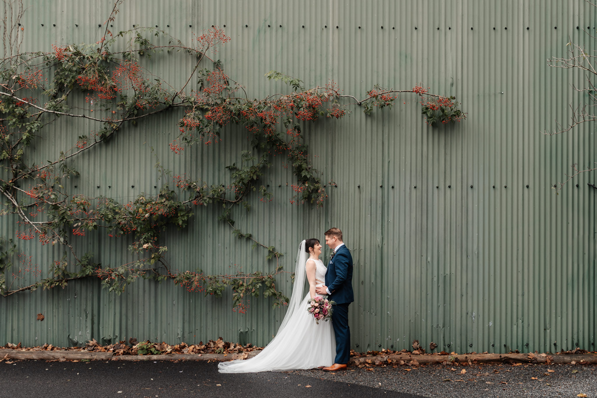 clock barn wedding photograher with bride and groom by rustic barn